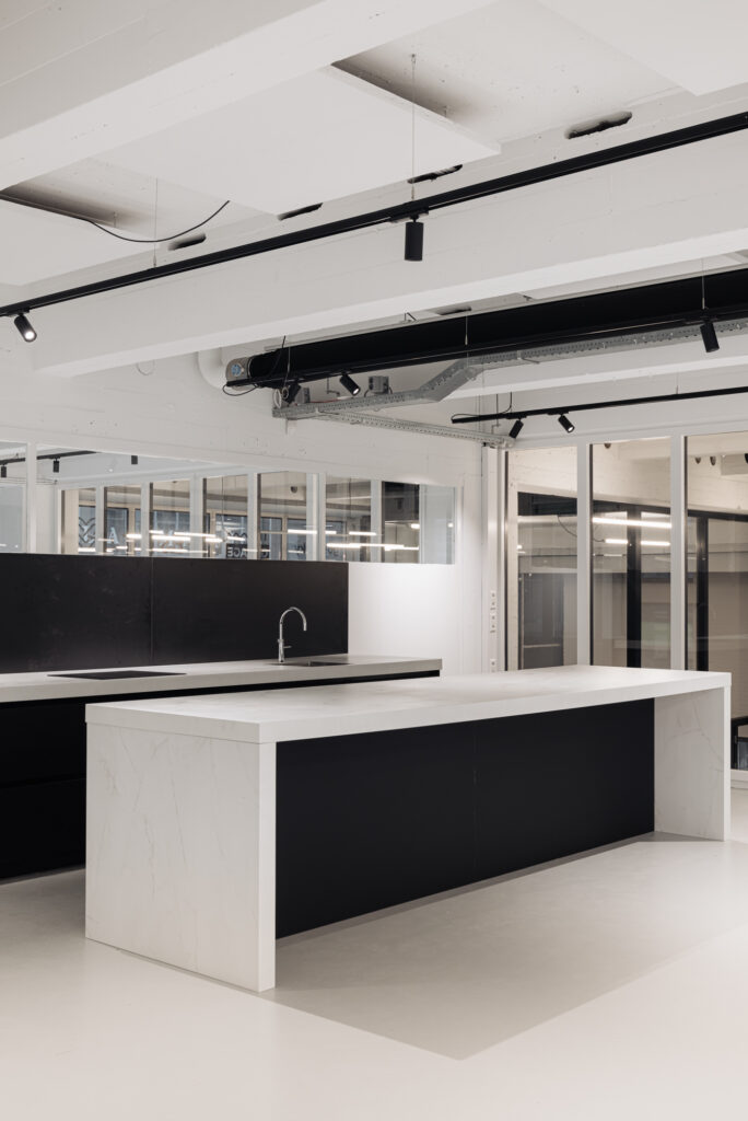 Moderne zwarte en witte keuken met kookeiland in een strak afgewerkt interieur aan de Generaal Vetterstraat.